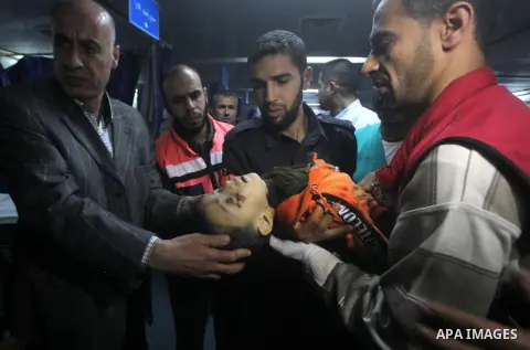 A Palestinian man carries the body of a baby boy who was killed in an Israeli air strike, during the visit by the Palestinian Prime Minister in the Gaza Strip Ismail Haniya and Egyptian Prime Minister Hisham Qandil (both...