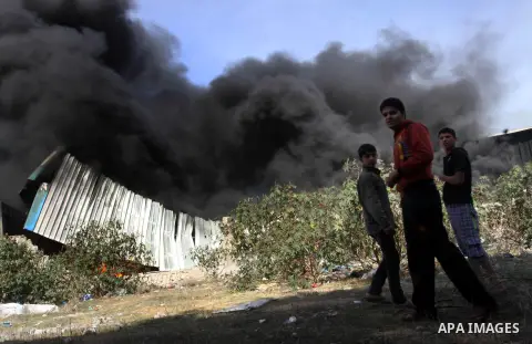 Palestinians stand near a factory which according to Palestinians was hit by an Israeli air strike in Gaza November 16, 2012. Egyptian Prime Minister Hisham Kandil arrived in the Gaza Strip on Friday to show solidarity w...