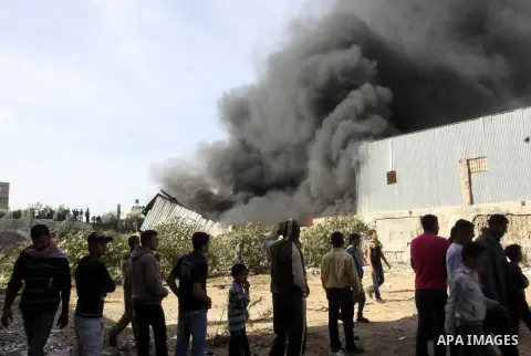 Palestinians stand near a factory which according to Palestinians was hit by an Israeli air strike in Gaza November 16, 2012. Egyptian Prime Minister Hisham Kandil arrived in the Gaza Strip on Friday to show solidarity w...