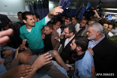 Palestinian Prime Minister in the Gaza Strip Ismail Haniyeh and Egypt's Prime Minister Hisham Kandil hold the hand of a patient, who was injured during an Israeli strike, during their visit to a hospital in Gaza City Nov...