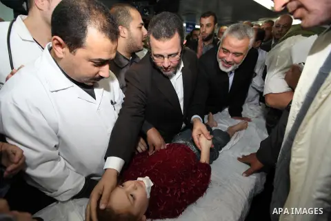 Palestinian Prime Minister in the Gaza Strip Ismail Haniyeh and Egypt's Prime Minister Hisham Kandil hold the hand of a Child, who was injured during an Israeli strike, during their visit to a hospital in Gaza City Novem...