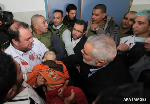 Palestinian Prime Minister in the Gaza Strip Ismail Haniyeh and Egypt's Prime Minister Hisham Kandil touch the body of a Palestinian boy, who was killed in an Israeli air strike, during a visit to a hospital in Gaza City...