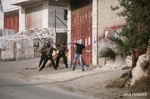 Palestinian demonstrators throw stones at Israeli troops during clashes following a protest against Israel's operations in Gaza Strip in the village of Beit Ummar near the West Bank city of Hebron on November, 16, 2012....
