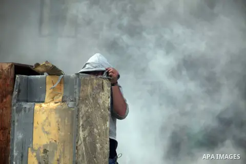 A Palestinian stone-thrower walks past smoke from burning tyres during clashes with Israeli security forces against Israel's military operation in Gaza, at Qalandia checkpoint near the West Bank city of Ramallah November...