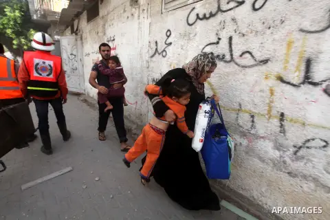 Palestinians carry their children and run cover from the Israeli air strikes in al-Shijaia in the east of Gaza city on, 18 November 2012. Israel bombed militant targets in Gaza for a fifth straight day on Sunday, launchi...