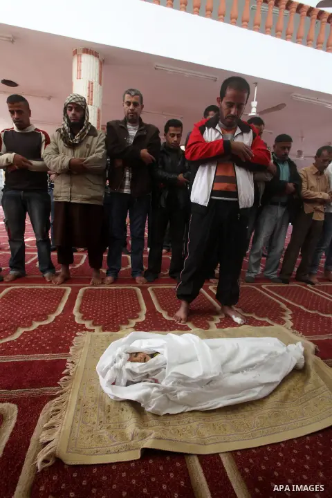 Palestinians pray over the body of one and a half year-old baby, Iyad Abu Khoussa, during his funeral at a mosque in Bureij Refugee Camp, central Gaza Strip, Sunday, Nov. 18, 2012. The baby boy was one of five Palestinia...