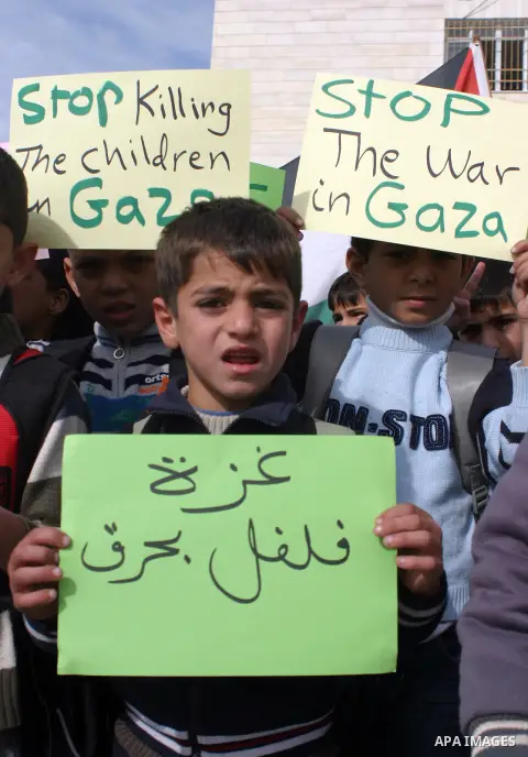 Palestinian children shout slogans and hold placards during a protest in solidarity with the children of Gaza, in the West Bank city of Hebron, on November 18, 2012. Israeli aircraft killed five Palestinian children in o...