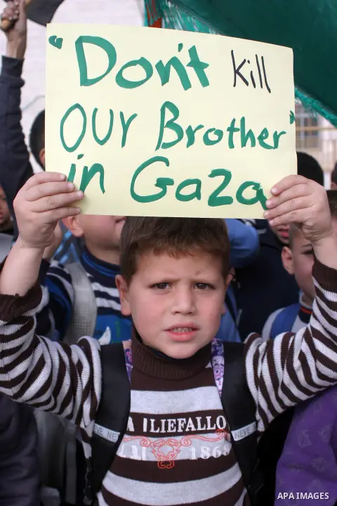 Palestinian children shout slogans and hold placards during a protest in solidarity with the children of Gaza, in the West Bank city of Hebron, on November 18, 2012. Israeli aircraft killed five Palestinian children in o...