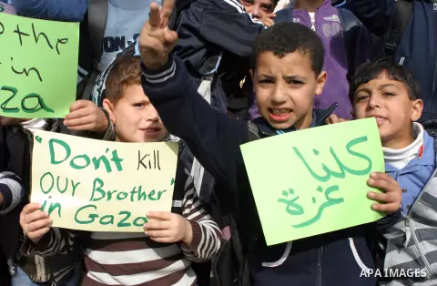 Palestinian children shout slogans and hold placards during a protest in solidarity with the children of Gaza, in the West Bank city of Hebron, on November 18, 2012. Israeli aircraft killed five Palestinian children in o...