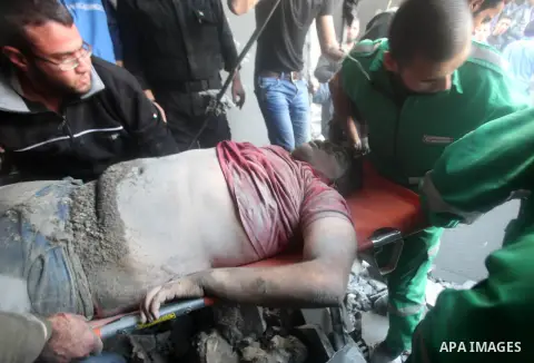 Palestinians carry the dead body of a man from the al-Dallu family out from the rubble after an Israeli airstrike in Gaza City, on November 18, 2012. Ten Palestinian civilians were killed on Sunday in an Israeli air stri...