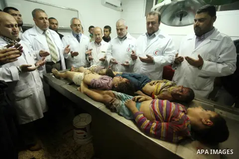 Palestinian doctors gather arround the bodies of four children from the al-Dallu family lay in a hospital after an Israeli missile struck a family home in Gaza City, on November 18, 2012. Ten Palestinian civilians were k...