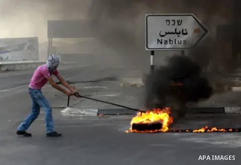 A Palestinian protester burns a tire during clashes following a protest against Israel's operations in the Gaza Strip, at Howwara checkpoint near Nablus, the West Bank, 18 November 2012. Reports state that the Israeli mi...