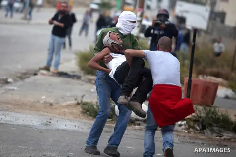 Palestinians carry a wounded man during clashes outside Ofer prison near the West Bank city of Ramallah November 18, 2012. The clashes broke out following a protest against Israel's military operation in the Gaza strip....