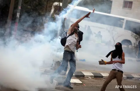 Palestinian protesters take cover from tear gas fired by Israeli border policemen during clashes outside Ofer prison near the West Bank city of Ramallah November 18, 2012. The clashes broke out following a protest agains...