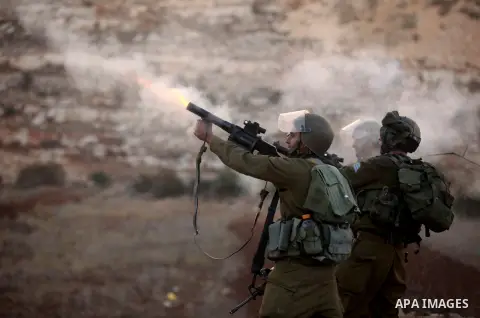 An Israeli border policeman shoots a tear gas canister at Palestinian protesters during clashes outside Ofer prison near the West Bank city of Ramallah November 18, 2012. The clashes broke out following a protest against...