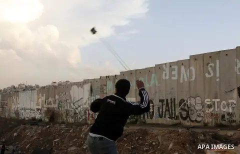 A Palestinian protester throws stones at Israeli border policemen during a Palestinian protest at Damascus Gate in East Jerusalem, 18 November 2012, showing solidarity with the Palestinians in the Gaza Strip, as hostilit...