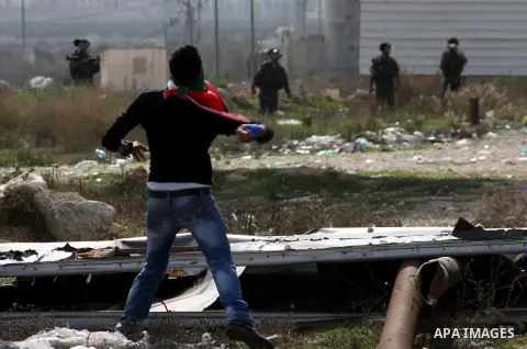 A Palestinian protester throws stones at Israeli soldiers during clashes following a protest against Israel's operations in the Gaza Strip, at Howwara checkpoint near Nablus, the West Bank, 17 November 2012. Reports stat...