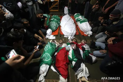 Palestinian mourners gather around the bodies of the al-Dallu family during their funeral in Gaza City, 19 November 2012. Nine members of the al-Dallu family died when Israeli forced hit their building in Gaza City one d...
