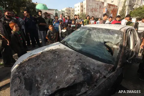 Palestinians gather around a destroyed car which targeted by Israeli airstrike in the northen Gaza city, 19 November, 2012. Israeli aircraft killed A Palestinian and wounded two others in the raid. Media reports that Isr...