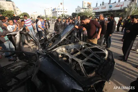 Palestinians gather around a destroyed car which targeted by Israeli airstrike in the northen Gaza city, 19 November, 2012. Israeli aircraft killed A Palestinian and wounded two others in the raid. Media reports that Isr...