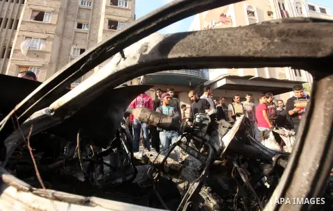 Palestinians gather around a destroyed car which targeted by Israeli airstrike in the northen Gaza city, 19 November, 2012. Israeli aircraft killed A Palestinian and wounded two others in the raid. Media reports that Isr...