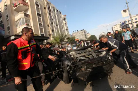 Palestinians gather around a destroyed car which targeted by Israeli airstrike in the northen Gaza city, 19 November, 2012. Israeli aircraft killed A Palestinian and wounded two others in the raid. Media reports that Isr...