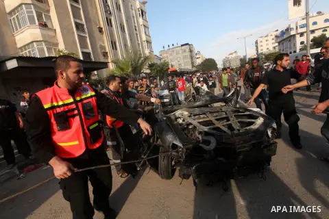 Palestinians gather around a destroyed car which targeted by Israeli airstrike in the northen Gaza city, 19 November, 2012. Israeli aircraft killed A Palestinian and wounded two others in the raid. Media reports that Isr...