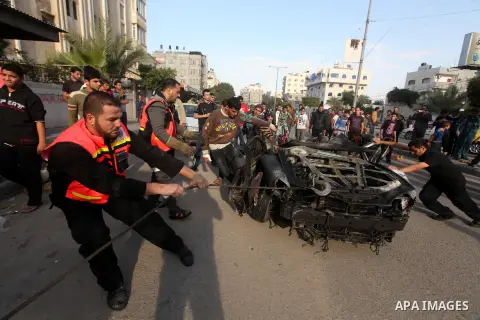 Palestinians gather around a destroyed car which targeted by Israeli airstrike in the northen Gaza city, 19 November, 2012. Israeli aircraft killed A Palestinian and wounded two others in the raid. Media reports that Isr...