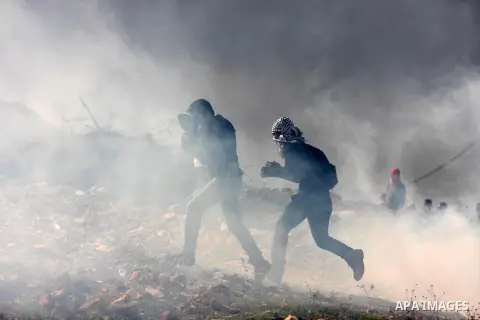 Palestinians run cover from tear gas during minor clashes against Israel's military operation in the Gaza Strip, in the West Bank village of Birzeit, near Ramallah November 19, 2012. Israel bombed dozens of targets in Ga...