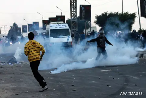 Palestinians run cover from tear gas during clashes against Israel's military operation in the Gaza Strip, in the West Bank city of Nablus on November 19, 2012. Israeli air strikes killed 22 Palestinians, hiking the Gaza...