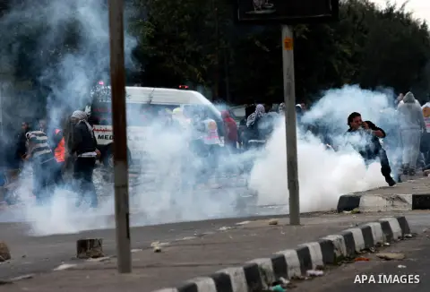 Palestinians take cover from tear gas during clashes against Israel's military operation in the Gaza Strip, in the West Bank city of Nablus on November 19, 2012. Israeli air strikes killed 22 Palestinians, hiking the Gaz...