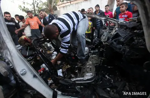 Palestinian gather arround a destroyed car following an Israeli strike in Gaza City on November 20, 2012. Israel's air force dropped leaflets across several districts of Gaza City urging people to evacuate their homes "i...