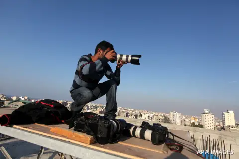 A Palestinian photographer takes pictures on a building in Gaza city, on November 20, 2012. Two Palestinian journalists were killed in an Israeli airstrike on Gaza City Tuesday evening, after media buildings were hit by...