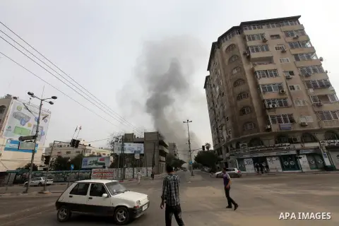 Palestinians look at smoke as rises from a building in an Israeli airstrike in Gaza City, 21 November 2012. Palestinian militants renewed their rocket fire on Israel 21 November and Israel continued pounding targets in t...