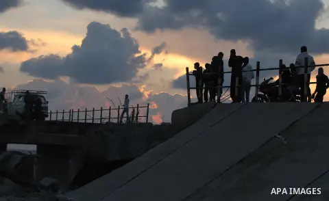 Palestinians look at Wadi Gaza bridge, a strategic link between the northern and southern areas of the Gaza Strip, following an Israeli air strike, November 23, 2012. Palestinians and Israelis on both sides of the Gaza b...