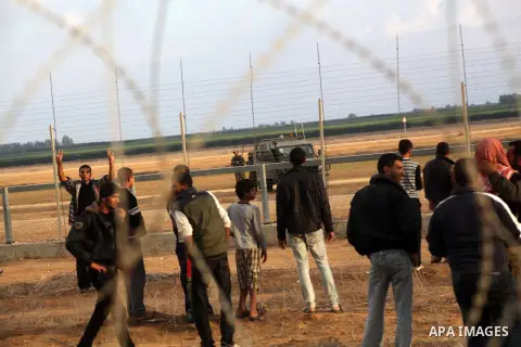 Palestinians stand near the Israeli Gaza border fence in east of Khan Younis, southern Gaza Strip, Friday, Nov. 23, 2012. Hundreds of Gaza crowds surged toward Israel's border fence with the Hamas-ruled territory, in a n...