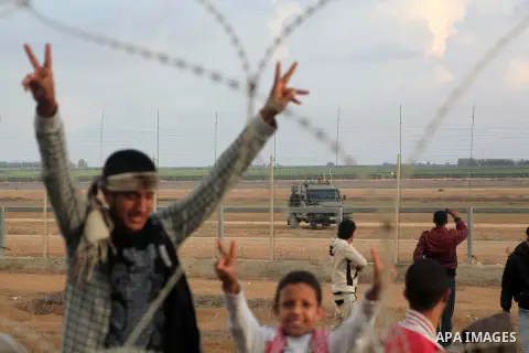 Palestinians stand near the Israeli Gaza border fence in east of Khan Younis, southern Gaza Strip, Friday, Nov. 23, 2012. Hundreds of Gaza crowds surged toward Israel's border fence with the Hamas-ruled territory, in a n...