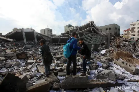 Palestinians school buys walk on the rubble of a building destroyed during earlier Israeli bombardment, as they make their way to their nearby school in Gaza City, on November 24, 2012, three days after a truce was decla...