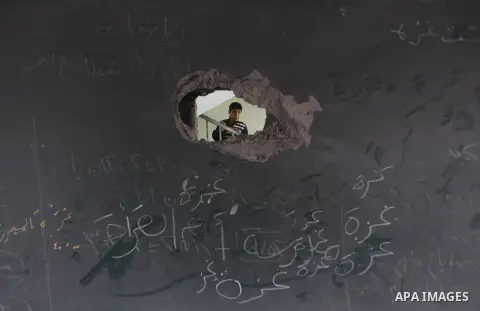 A Palestinian school boy looks through a hole at their damaged United Nations run school in Gaza City, on November 24, 2012, three days after a truce was declared between Israel and Hamas. Gaza's children, virtually abse...