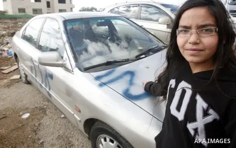 A Palestinian girl stands next to a car with a graffiti reading in Hebrew "Gaza: the price to pay" in the Palestinian neighborhood of Shuafat in Israeli annexed East Jerusalem, , on November 25, 2012. Unknown assailants...