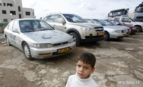 A Palestinian boy stands next to a car with a graffiti reading in Hebrew "Gaza: the price to pay" in the Palestinian neighborhood of Shuafat in Israeli annexed East Jerusalem, , on November 25, 2012. Unknown assailants v...