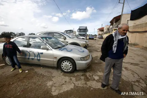 A Palestinian boy stands next to a car with a graffiti reading in Hebrew "Gaza: the price to pay" in the Palestinian neighborhood of Shuafat in Israeli annexed East Jerusalem, , on November 25, 2012. Unknown assailants v...