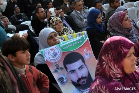 Palestinian women hold a poster of Palestinian prisoners during a protest calling for the release them from Israeli jails and in support of prisoners on hunger strike in front of Red Cross, in Gaza city on 26 November 20...