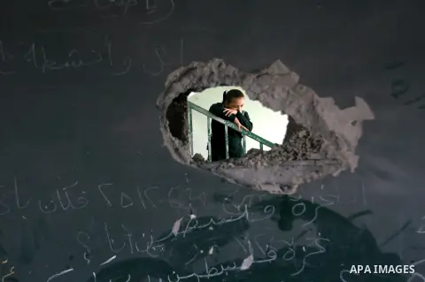 A Palestinian school girl appears through a hole in a wall in a damaged school in Rafah southern Gaza strip on November 26, 2012. The school was damaged some days ago, before a truce between Hamas and Israel ended eight...