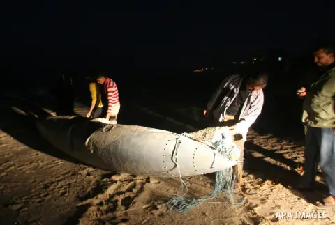 Palestinians stand next to what they said a part of an Israeli warplane on the beach of Rafah in southern Gaza strip, November 26, 2012. According to Hamas sources, Palestinian militant groups in the Gaza strip shot down...