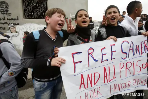 Relatives of Palestinians jailed in Israel demonstrate with placards of a detained prisoner, Tareq Issawi, who is on a hunger strike, as they protest for his release in Jerusalem, 27 November 2012. Photo by Mahfouz Abu T...
