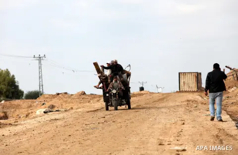Palestinians ride their tricycle near the smuggling tunnels dug beneath the Egyptian-Gaza border in Rafah, in the southern Gaza Strip November 27, 2012. Knee-deep in craters carved out by Israeli air strikes, Palestinian...