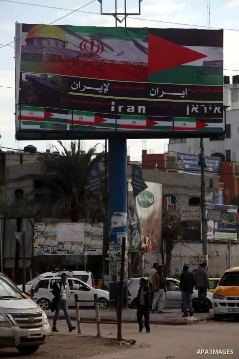 Palestinians walk next to a placard reads in Arabic "Thanks for Iran" in Gaza city on November 27, 2012. The commander of Iran's elite Revolutionary Guards has publicly admitted that his forces supplied the Islamic milit...