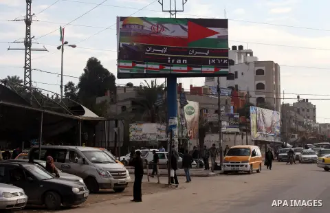 Palestinians walk next to a placard reads in Arabic "Thanks for Iran" in Gaza city on November 27, 2012. The commander of Iran's elite Revolutionary Guards has publicly admitted that his forces supplied the Islamic milit...