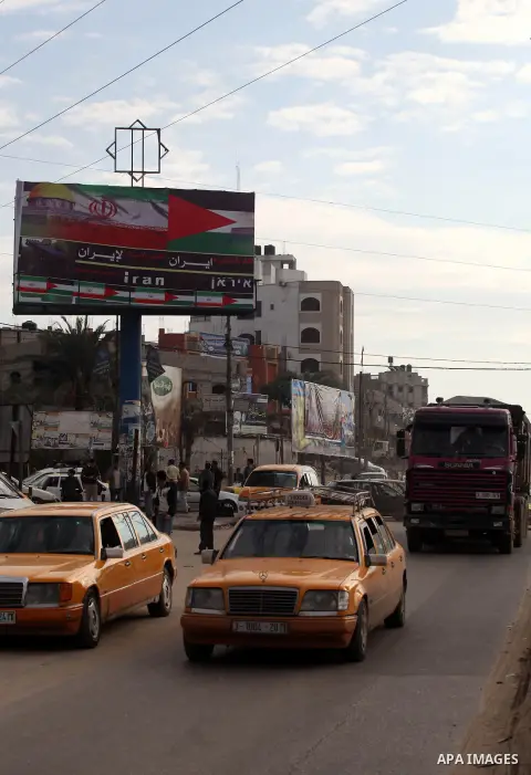 Palestinians walk next to a placard reads in Arabic "Thanks for Iran" in Gaza city on November 27, 2012. The commander of Iran's elite Revolutionary Guards has publicly admitted that his forces supplied the Islamic milit...
